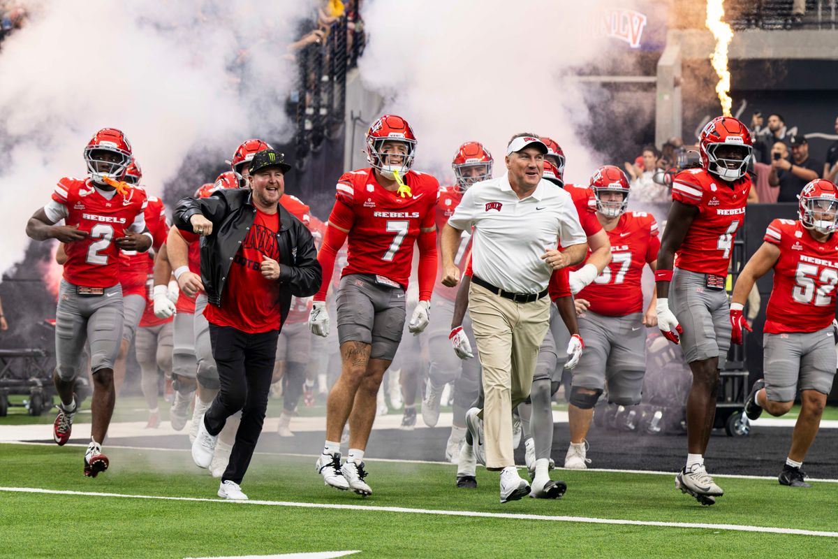 UNLV Rebels head coach Dan Mullen runs with retired NASCAR driver Kurt Busch prior to a game against the California Golden Bears on Saturday, October 03, 2026, at Allegiant Stadium in Las Vegas, Nevada.