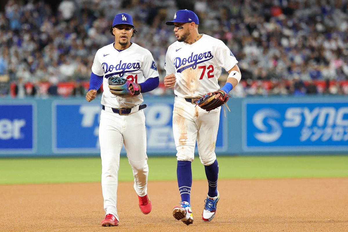 Miguel Rojas #72 and Santiago Espinal #21 of the Los Angeles Dodgers discuss strategy during an MLB game against the New York Mets on April 13, 2026 in Los Angeles, CA. 
